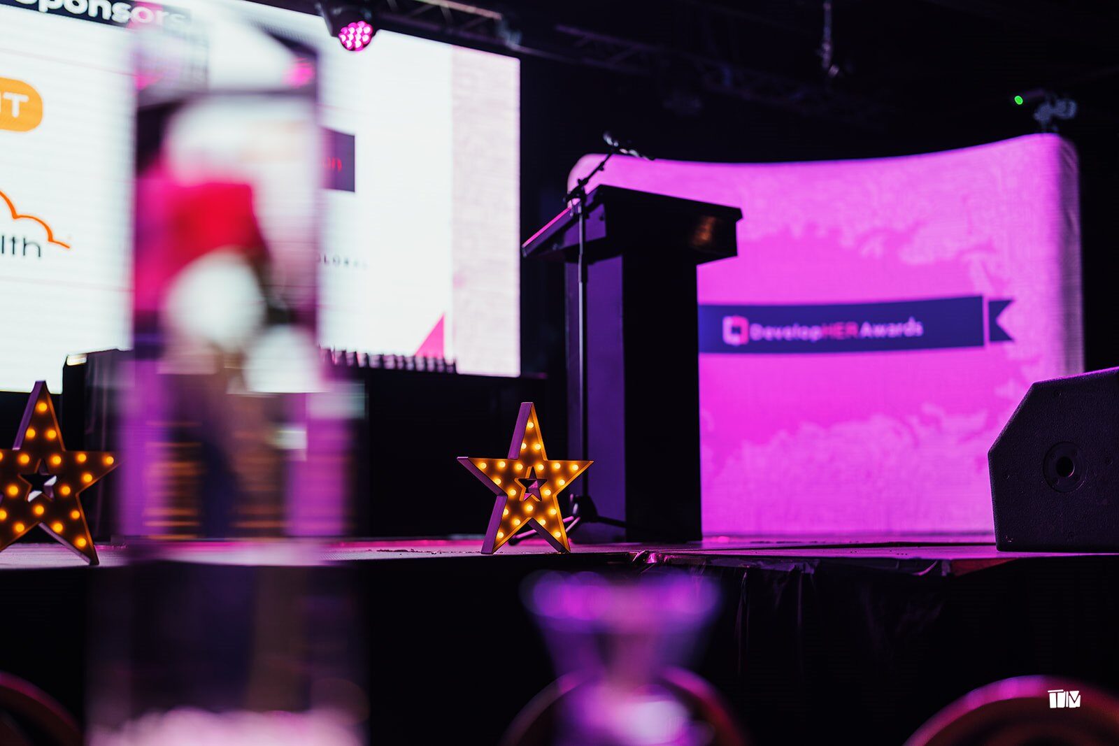 The DevelopHER Awards stage lit in pink, with the lectern and light-up stars