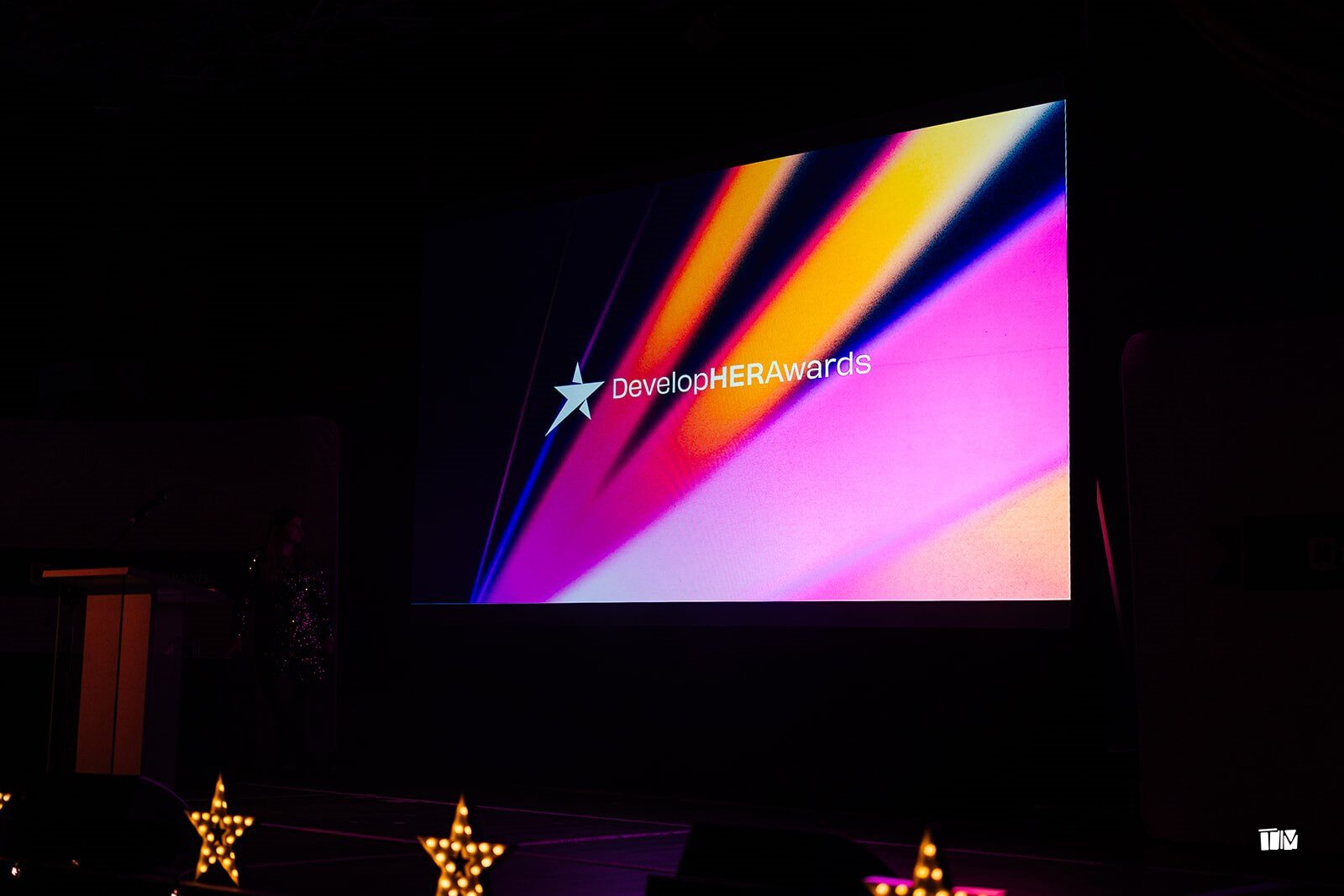 The DevelopHER Awards logo on a big screen at the ceremony venue